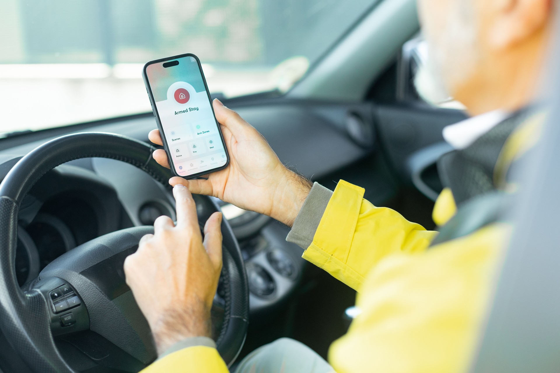 Mature man activating car alarm with his smartphone app