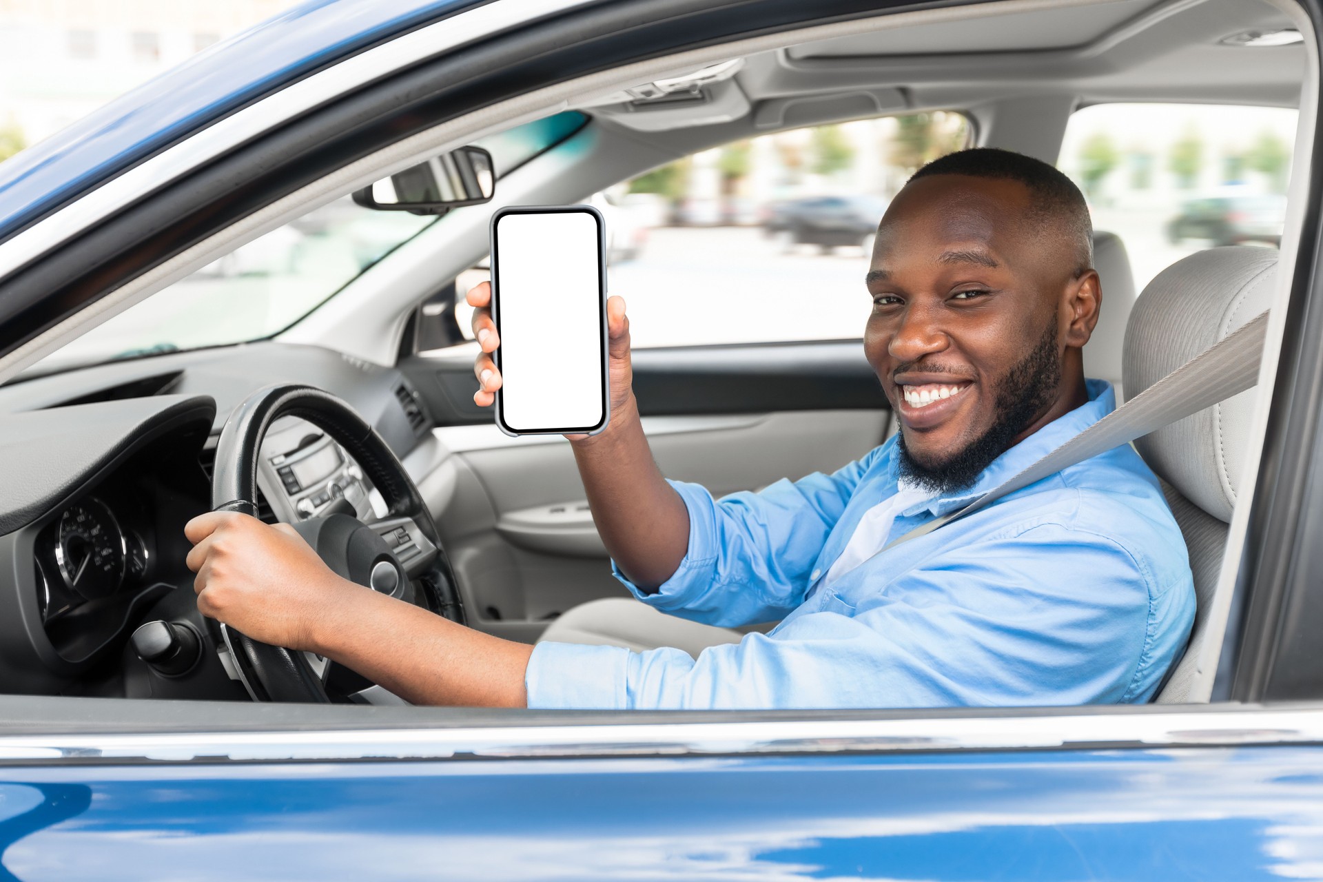 Happy black driver using showing smartphone with white empty screen